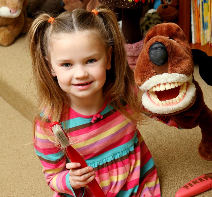 child with a tooth brushing dog toy and a tooth brush